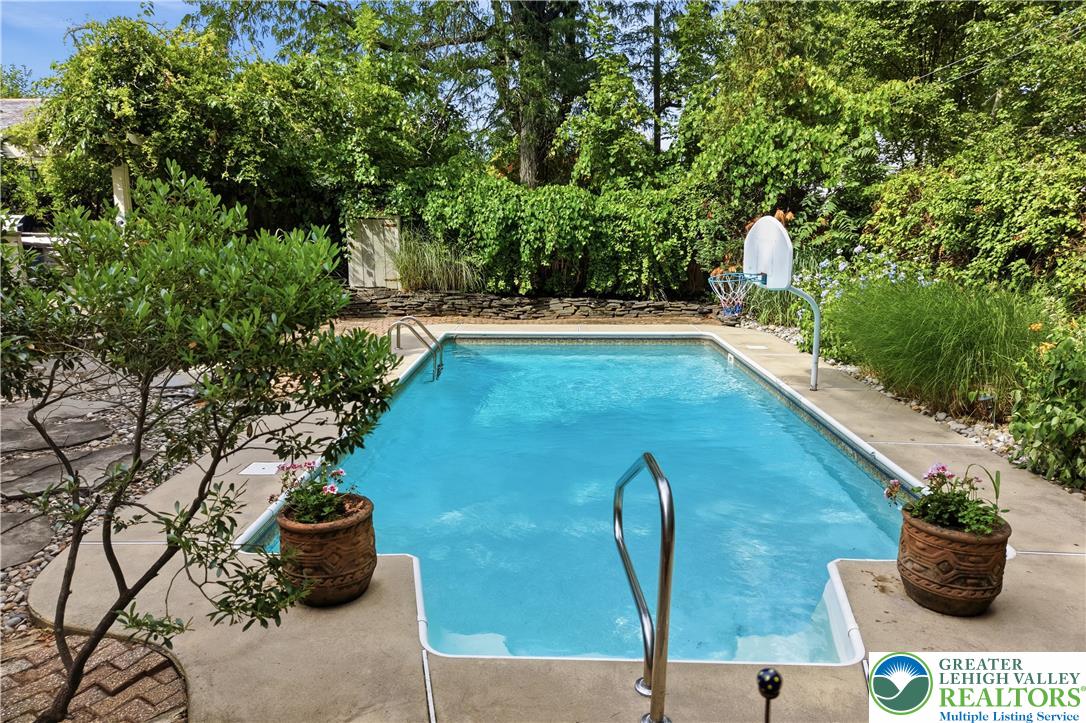 2014 Linden Street Bethlehem, PA 18017 - Photo 54 of 85 A tranquil backyard oasis features a glistening swimming pool surrounded by mature greenery and a basketball hoop.