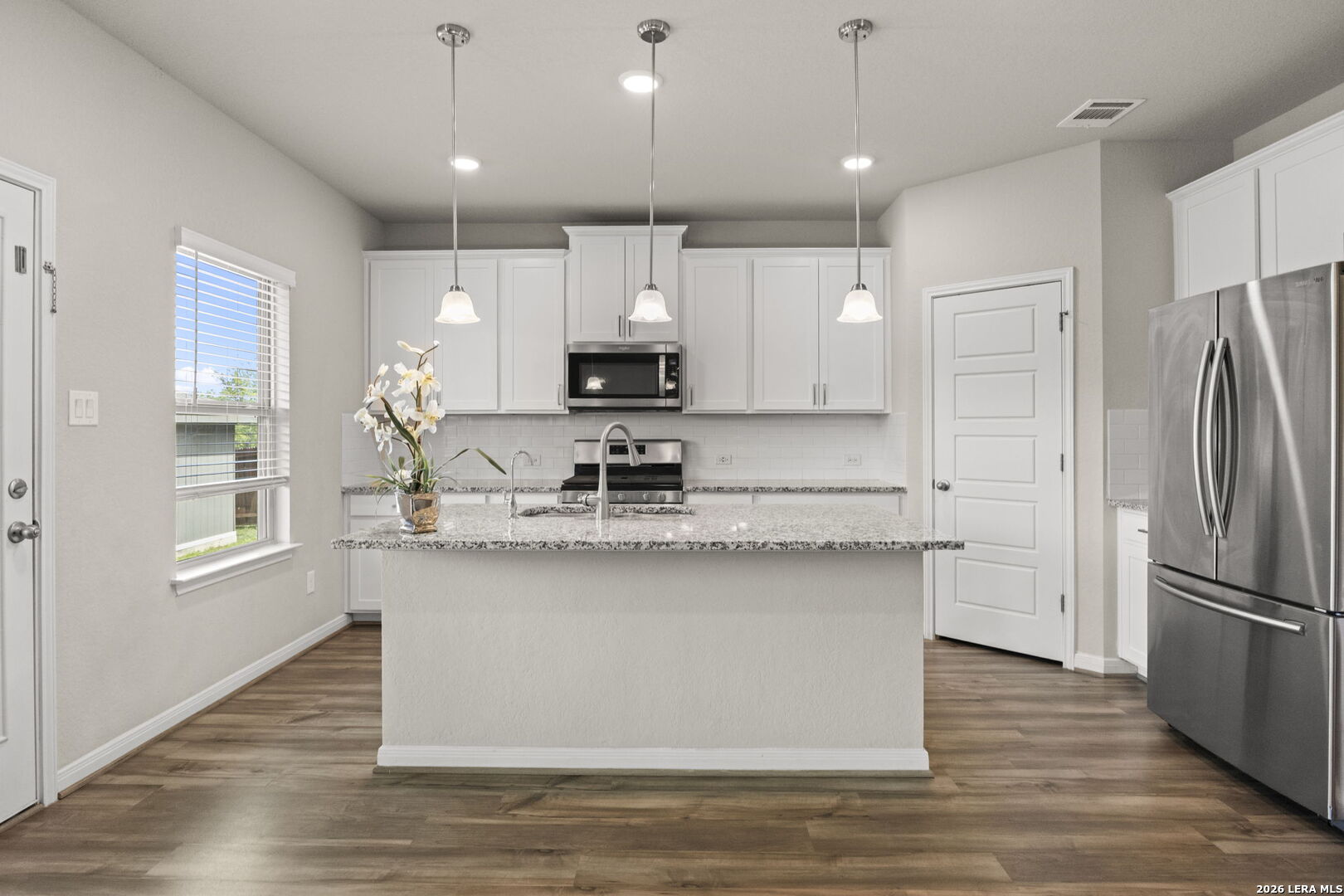 12221 Icon Ridge San Antonio, TX 78253 - Photo 13 of 46 a kitchen with stainless steel appliances granite countertop a refrigerator a sink dishwasher a stove and white cabinets with wooden floor
