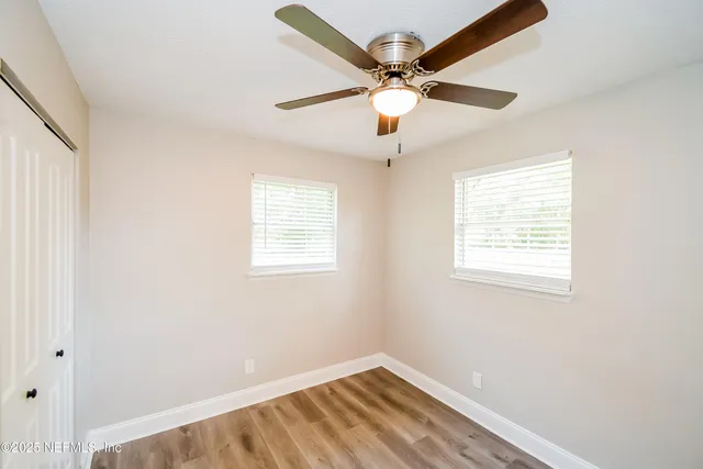 an empty room with a window and a fan