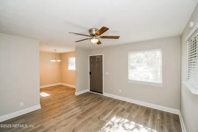 a view of an empty room with window and wooden floor