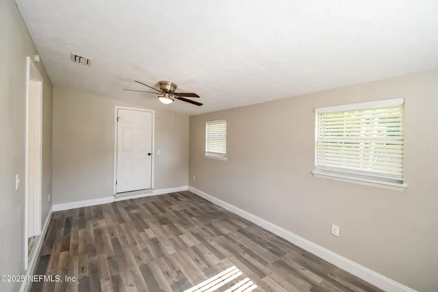 a view of a room with window ceiling fan and hardwood floor