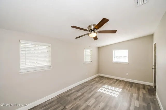 a view of a big room with wooden floor and windows