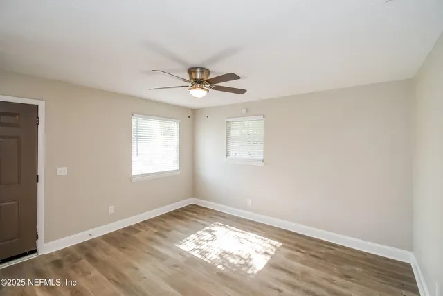 a view of a big room with wooden floor and a window