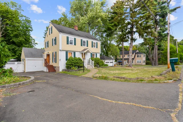 a view of a house with a big yard and large trees