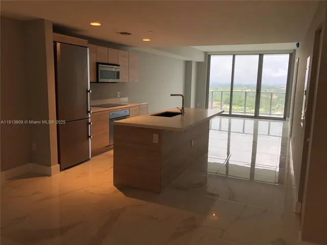 a large white kitchen with a sink and dishwasher a stove top oven with kitchen island