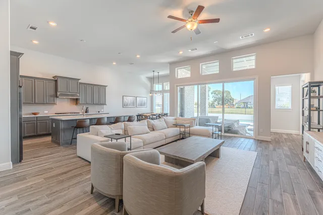 a living room with stainless steel appliances kitchen island granite countertop a sink a stove a dining table and chairs