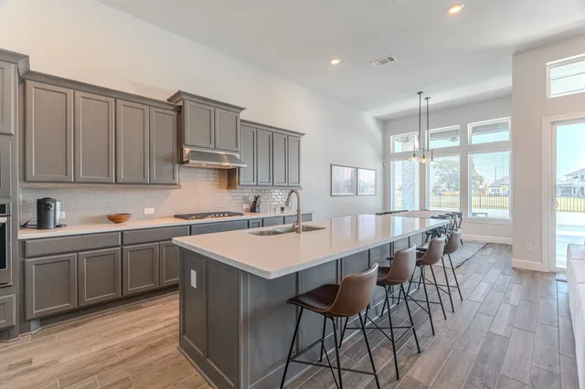 a large kitchen with cabinets chairs and wooden floor