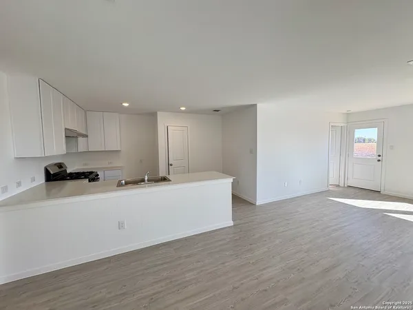 a large white kitchen with wooden floors and center island