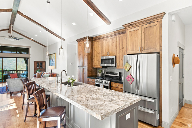 5207 North Oldgate Road Heber City, UT 84032 - Photo 12 of 58 Kitchen featuring a large island with an undermount sink, pendant lighting, stainless steel appliances, and wood cabinetry