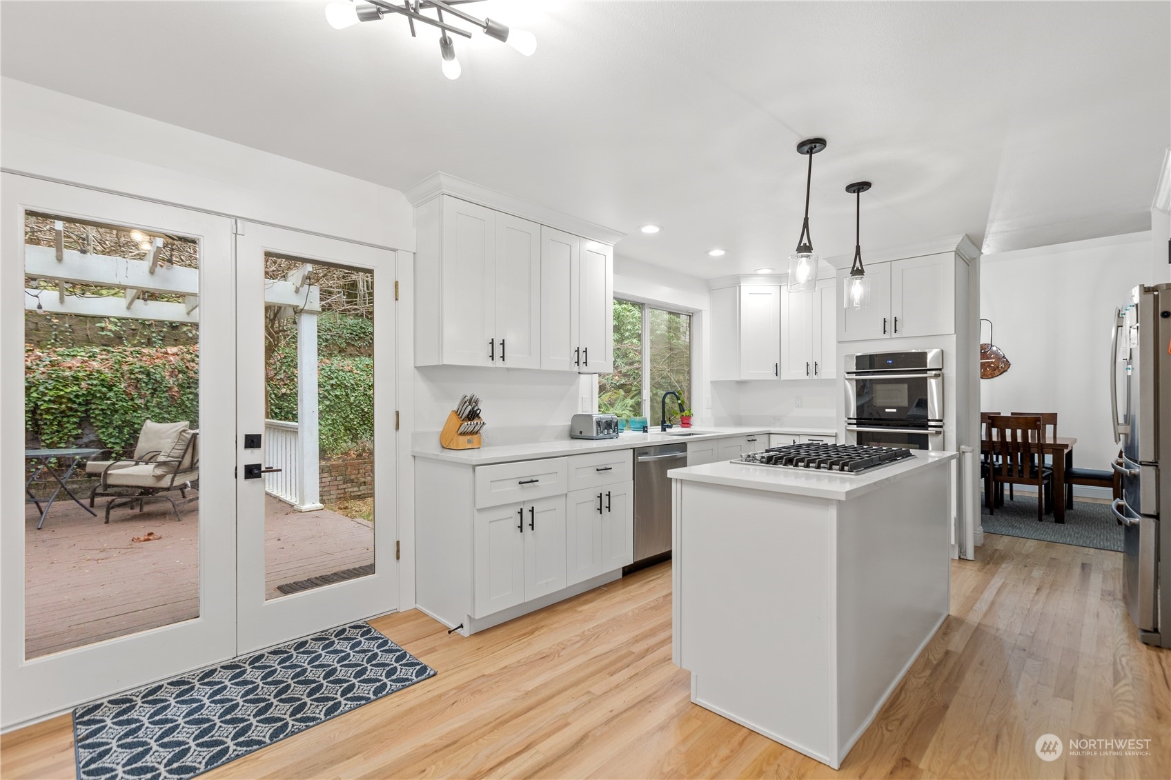 10411 Northeast 152nd Place Bothell, WA 98011 - Photo 11 of 38 a kitchen with a sink a stove a refrigerator and white cabinets with wooden floor