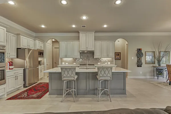 a kitchen with stainless steel appliances kitchen island granite countertop a refrigerator and cabinets