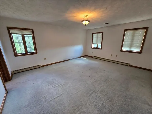 an empty room with a mirror and windows