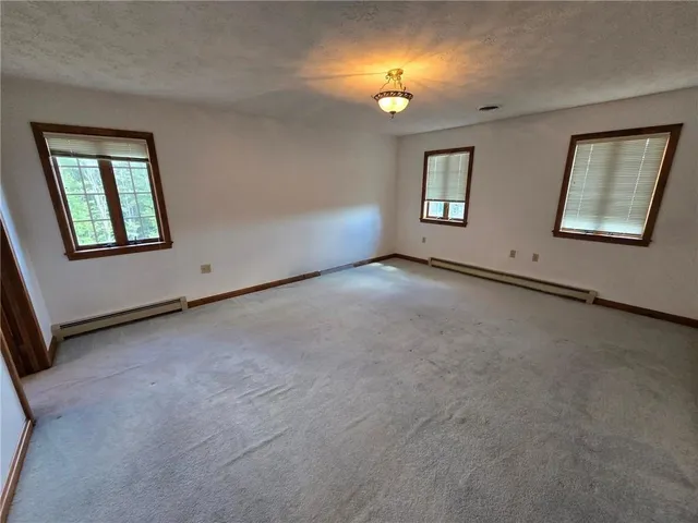 an empty room with a mirror and windows