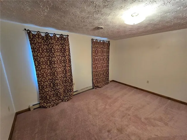 a view of an empty room with wooden floor and windows