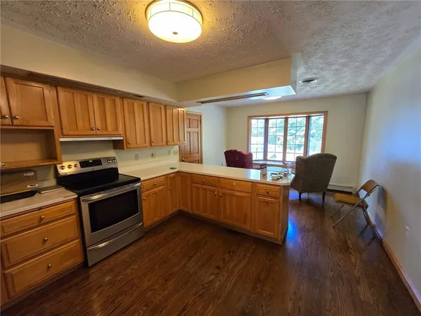 a kitchen with granite countertop a stove top oven a sink dishwasher a dining table and chairs with wooden floor