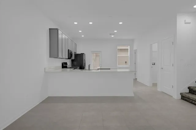 a view of kitchen refrigerator and white cabinets