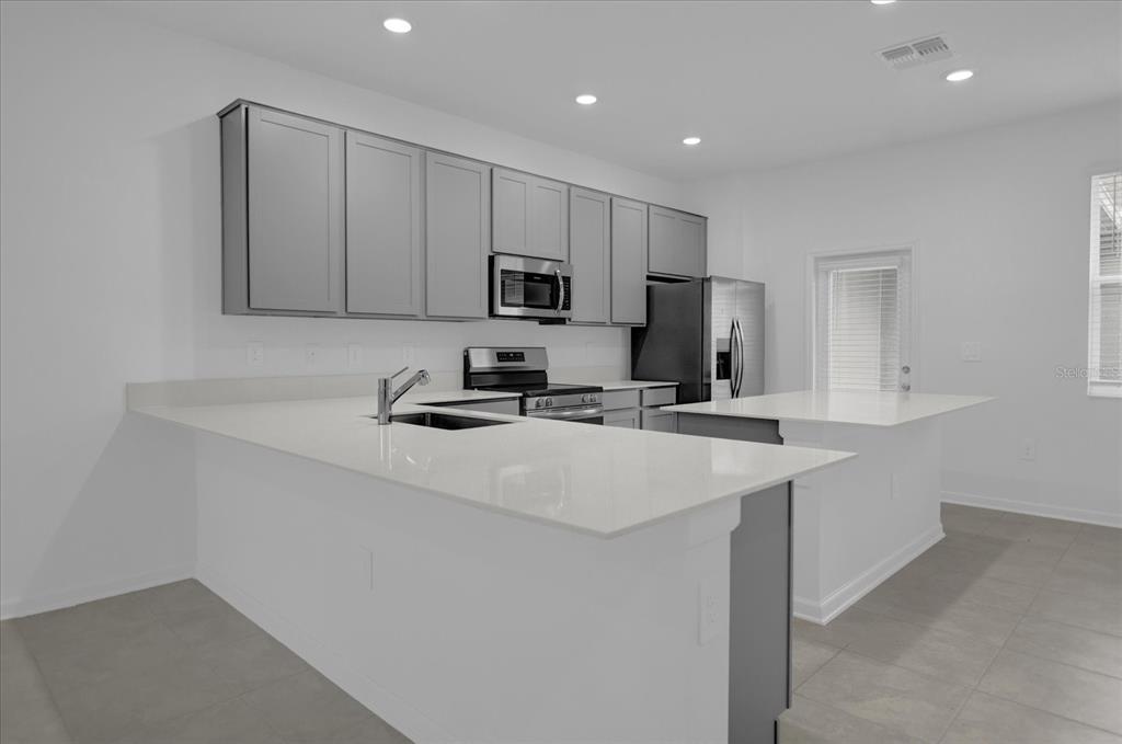 6049 Blissful Street Clermont, FL 34714 - Photo 9 of 25 a kitchen with kitchen island a sink stainless steel appliances and cabinets