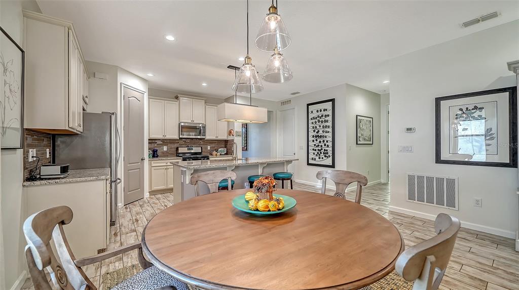 11211 Spring Gate Trail Lakewood Ranch, FL 34211 - Photo 19 of 51 a kitchen with stainless steel appliances granite countertop a stove a kitchen island a table and chairs