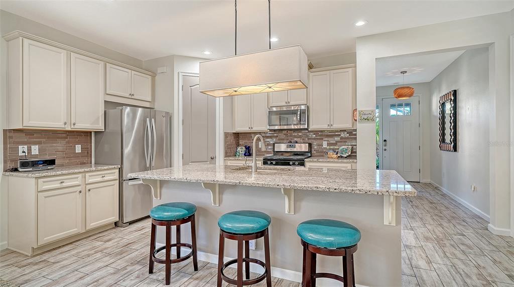 11211 Spring Gate Trail Lakewood Ranch, FL 34211 - Photo 20 of 51 a kitchen with stainless steel appliances a table chairs refrigerator and sink