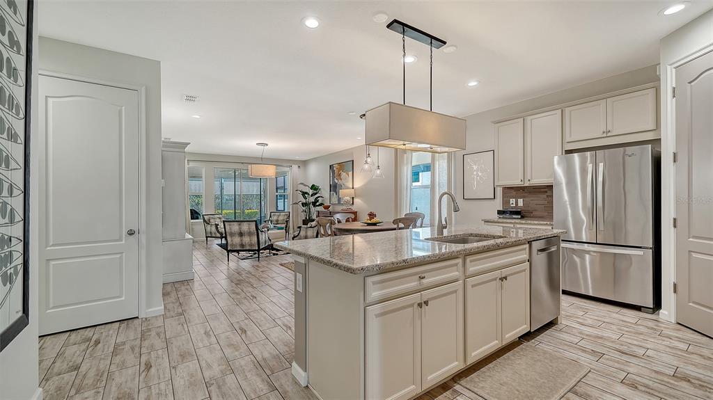 11211 Spring Gate Trail Lakewood Ranch, FL 34211 - Photo 9 of 51 a kitchen with kitchen island a counter top space a sink a refrigerator and wooden floor