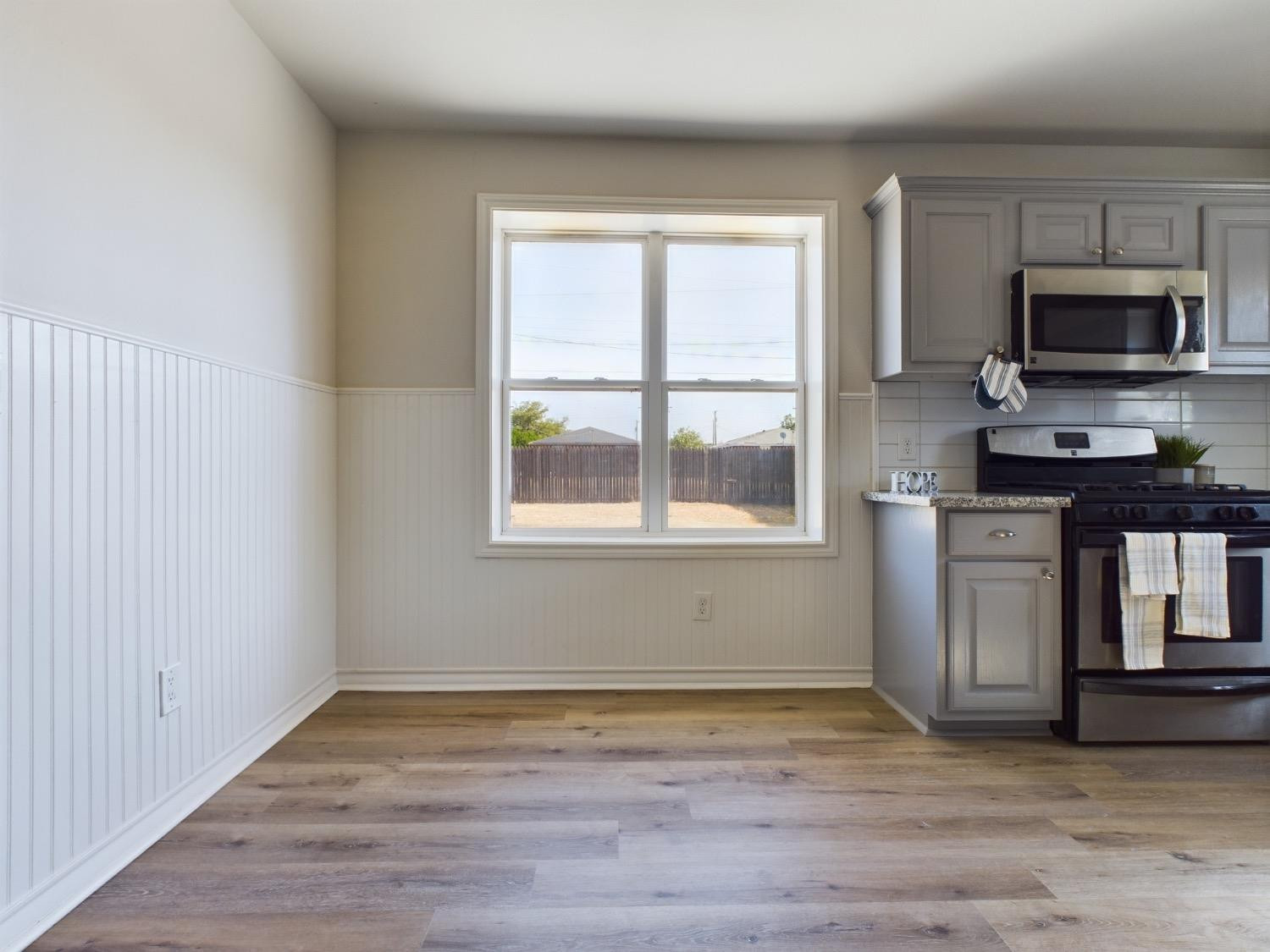6306 25th Street Lubbock, TX 79407 - Photo 24 of 37 a view of a kitchen and an empty room with wooden floor and windows