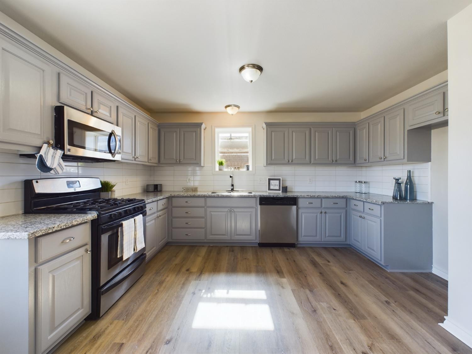 6306 25th Street Lubbock, TX 79407 - Photo 25 of 37 a kitchen with granite countertop a stove top oven sink and cabinets