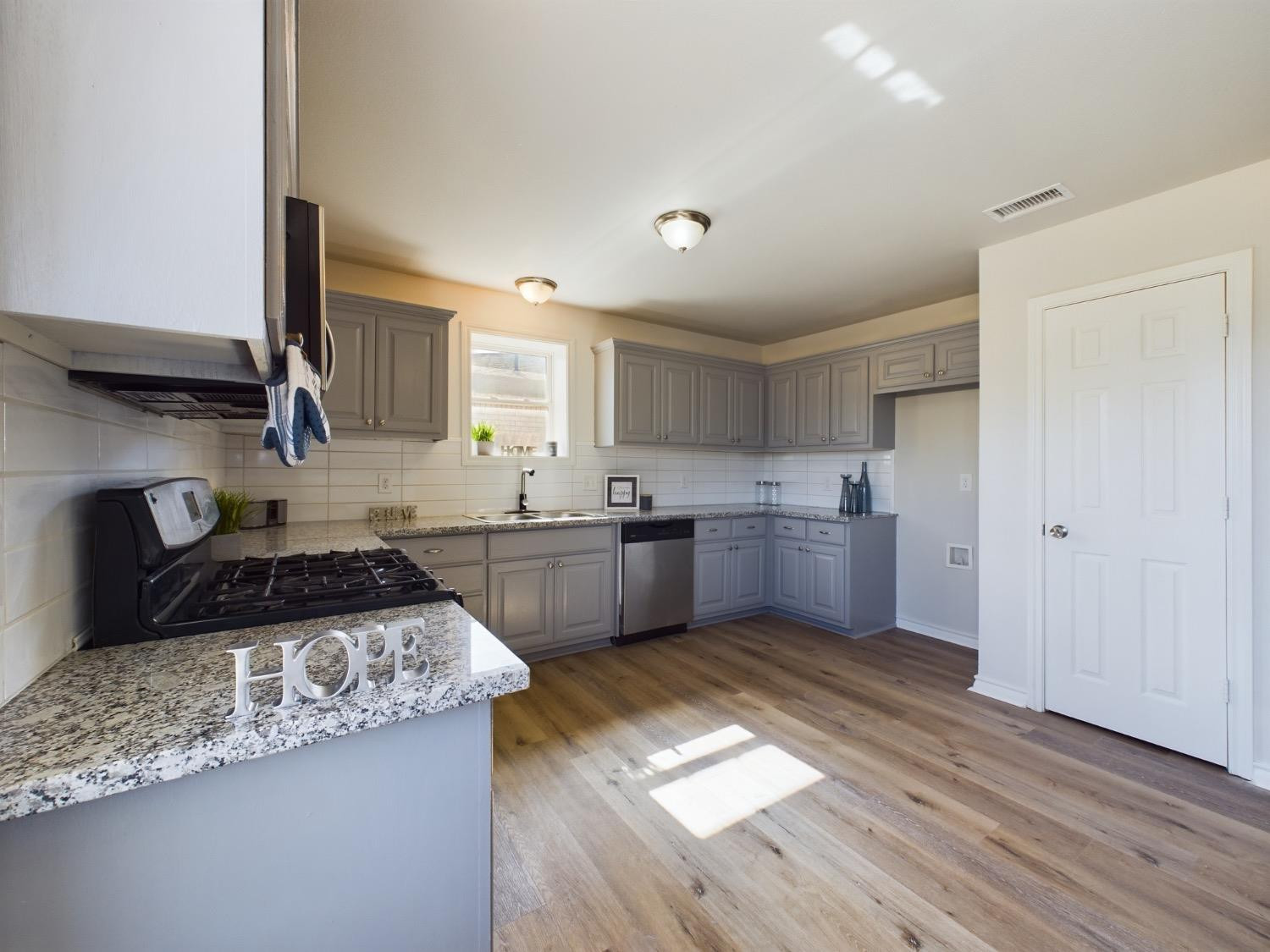 6306 25th Street Lubbock, TX 79407 - Photo 27 of 37 a kitchen with granite countertop a sink cabinets and wooden floor
