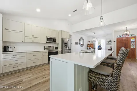 a kitchen with granite countertop a refrigerator a stove a sink dishwasher and white cabinets with wooden floor