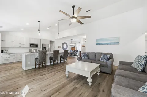 a living room with furniture kitchen view and a chandelier