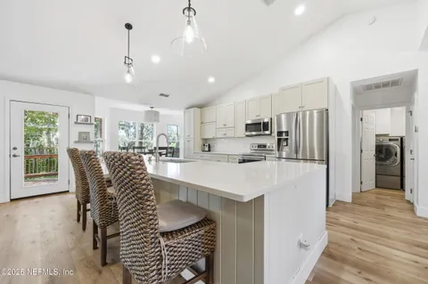 a kitchen with stainless steel appliances a dining table chairs refrigerator and microwave