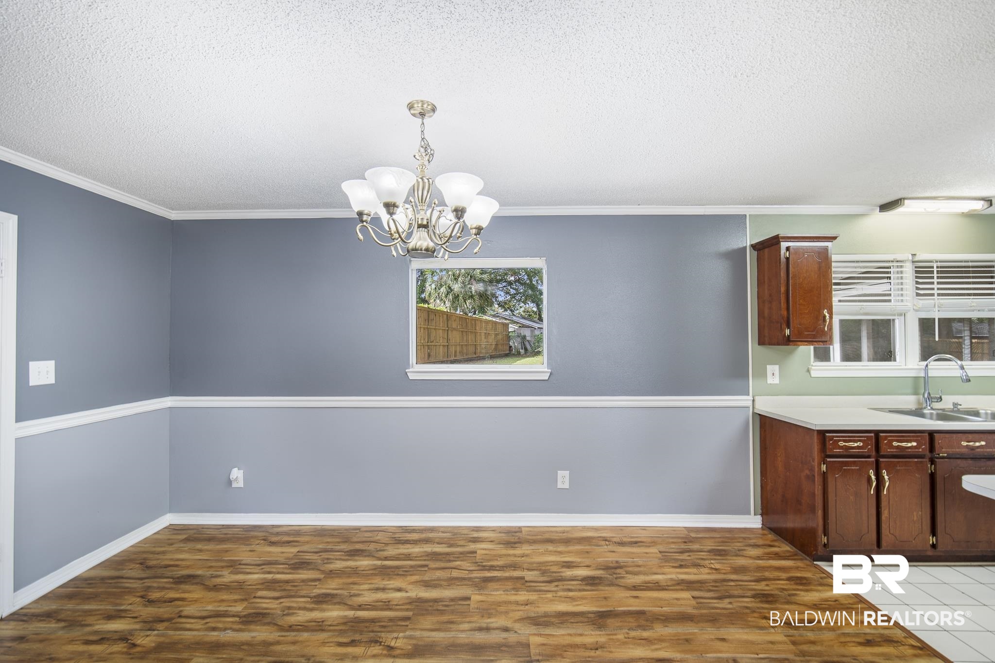 103 Ann Street Daphne, AL 36527 - Photo 5 of 23 Kitchen with a textured ceiling, light countertops, light wood-style flooring, crown molding, and a chandelier