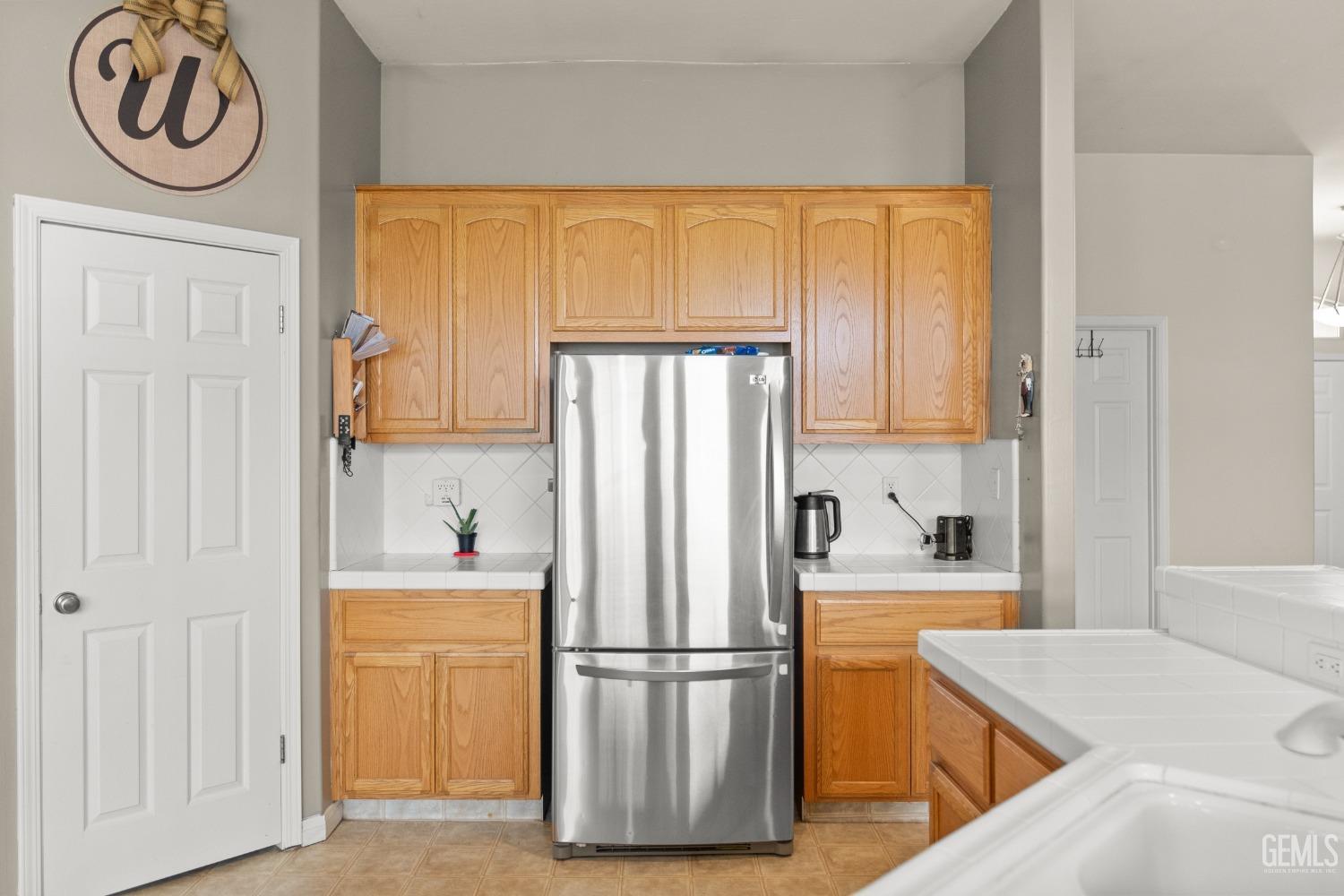 Undisclosed Address Bakersfield, CA 93306 - Photo 20 of 42 a kitchen with a refrigerator a stove top oven and cabinets