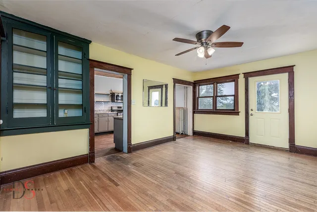 a view of an empty room with a window and wooden floor