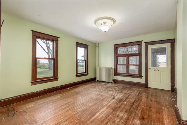 a view of an empty room with a window and wooden floor
