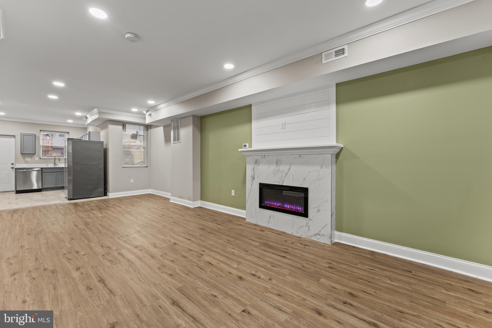 2560 Robb Street Baltimore, MD 21218 - Photo 6 of 19 a view of an empty room with wooden floor a fireplace and a window