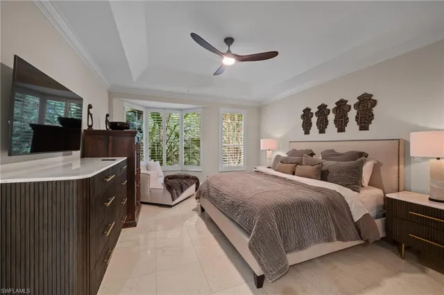 a spacious bedroom with a large bed and a flat tv screen