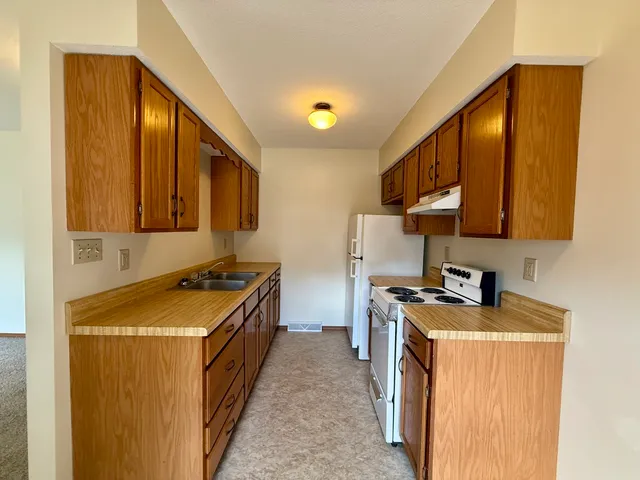 a kitchen with stainless steel appliances granite countertop a stove a sink a refrigerator and blue cabinets with wooden floor