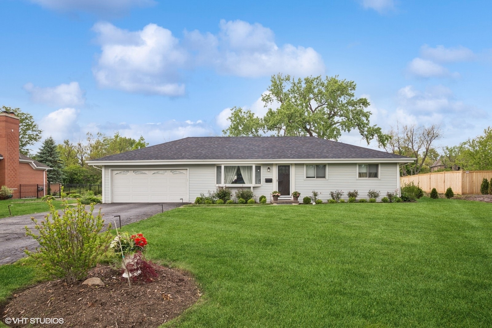 a view of a house with a big yard potted plants and a large tree