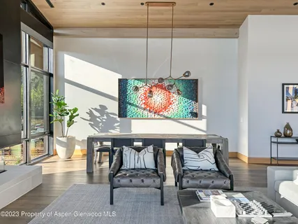 a view of a dining room with furniture one side kitchen view and wooden floor