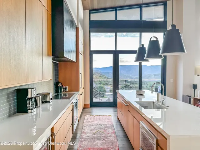 a large kitchen with kitchen island a large window a sink and stainless steel appliances