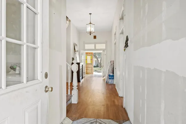 a hallway with wooden floor windows and a chandelier