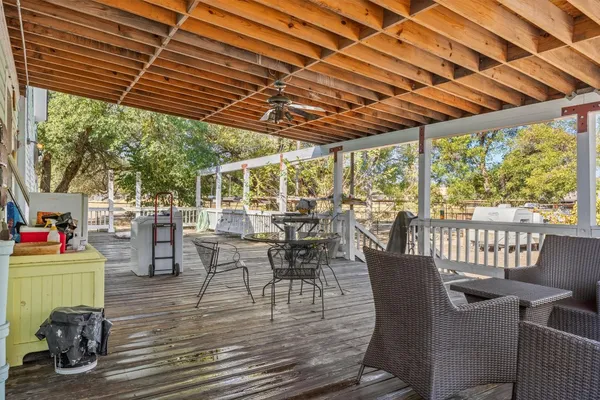 a view of a roof deck with table and chairs couches with wooden floor and fence