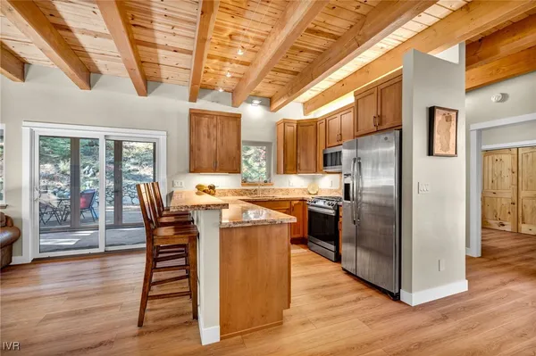 a kitchen with stainless steel appliances granite countertop a refrigerator a sink dishwasher a dining table and chairs with wooden floor