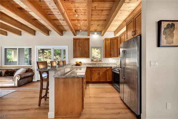 a kitchen with stainless steel appliances a dining table chairs and wooden floors