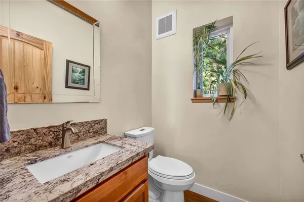 a bathroom with a granite countertop sink and a toilet