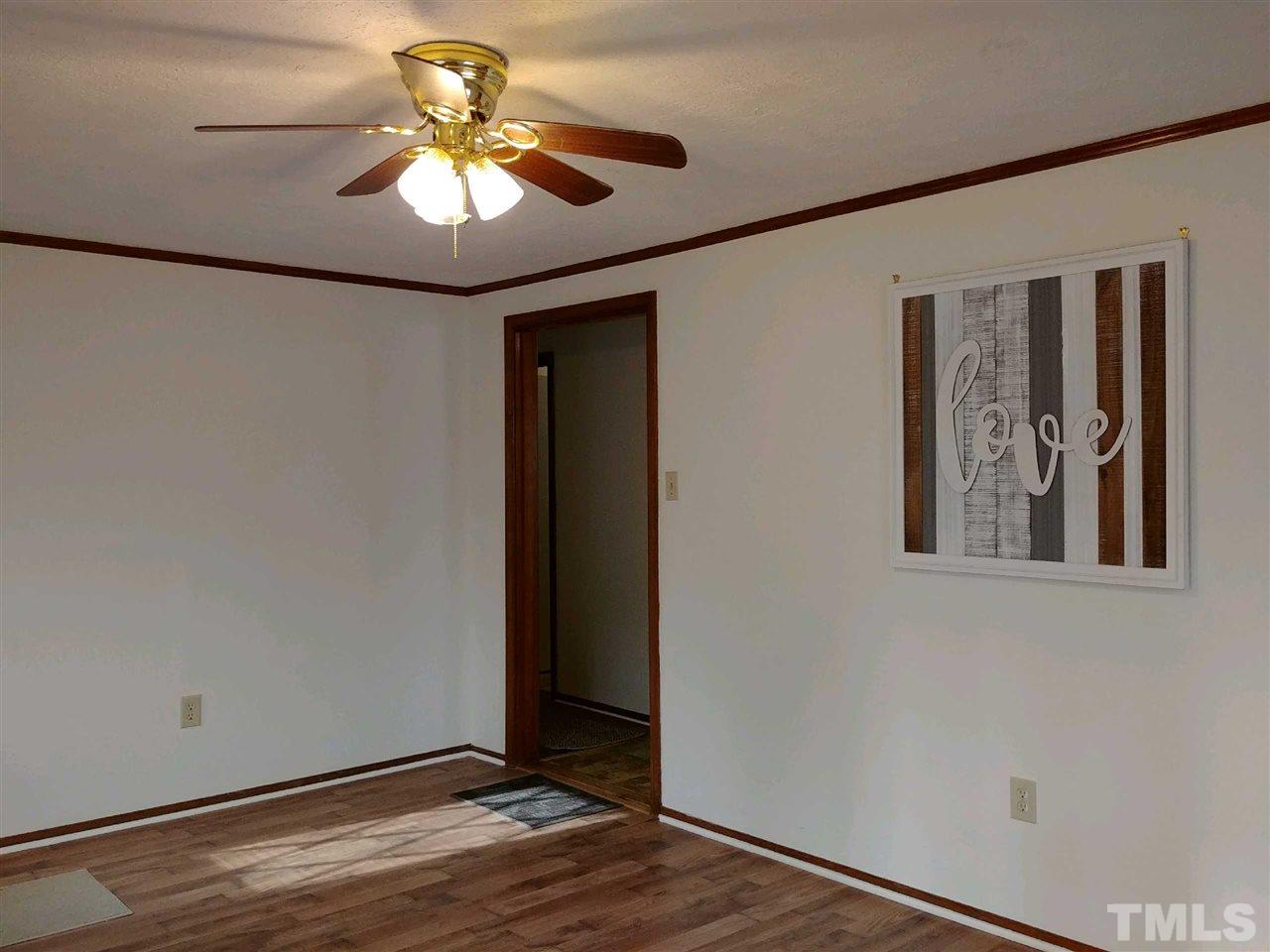 2312 Creech Road Raleigh, NC 27610 - Photo 3 of 11 an empty room with a chandelier fan and wooden floor
