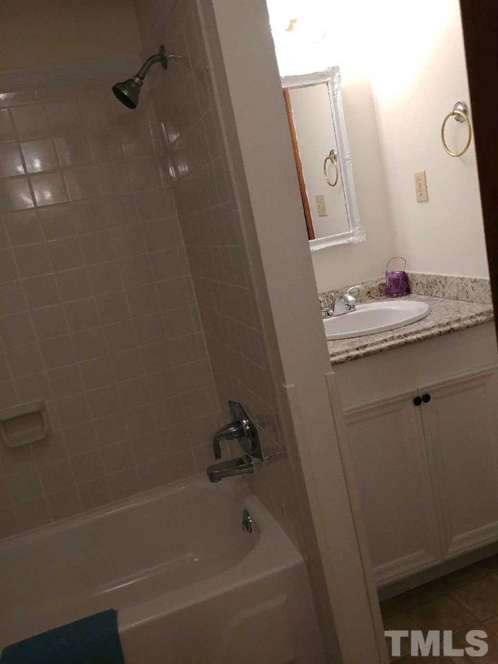 2312 Creech Road Raleigh, NC 27610 - Photo 9 of 11 a bathroom with a bathtub a sink and a mirror