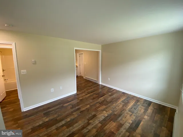 an empty room with wooden floor and entrance