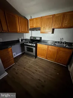 a kitchen with granite countertop a stove top oven a sink dishwasher and cabinets with wooden floor