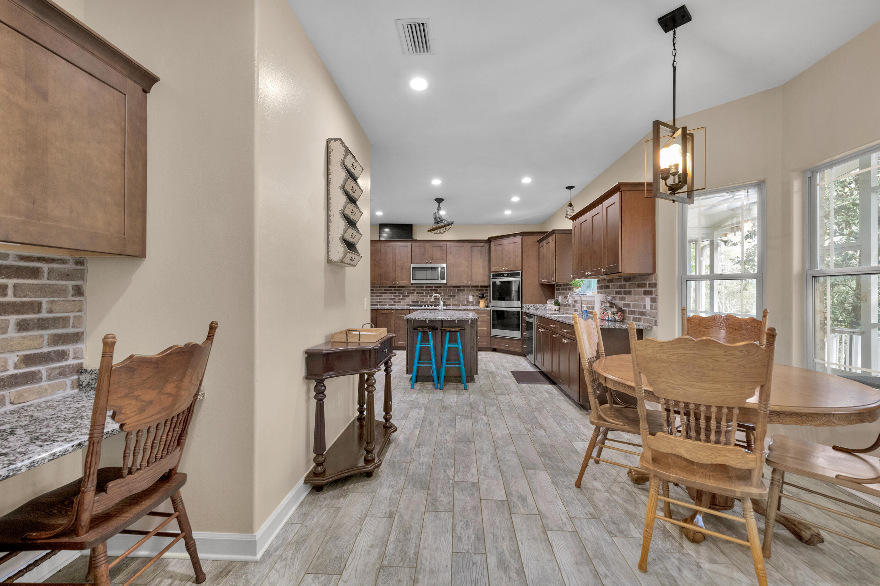 4475 Woodbridge Road Niceville, FL 32578 - Photo 16 of 49 a kitchen with stainless steel appliances kitchen island granite countertop a dining table chairs and a wooden floor
